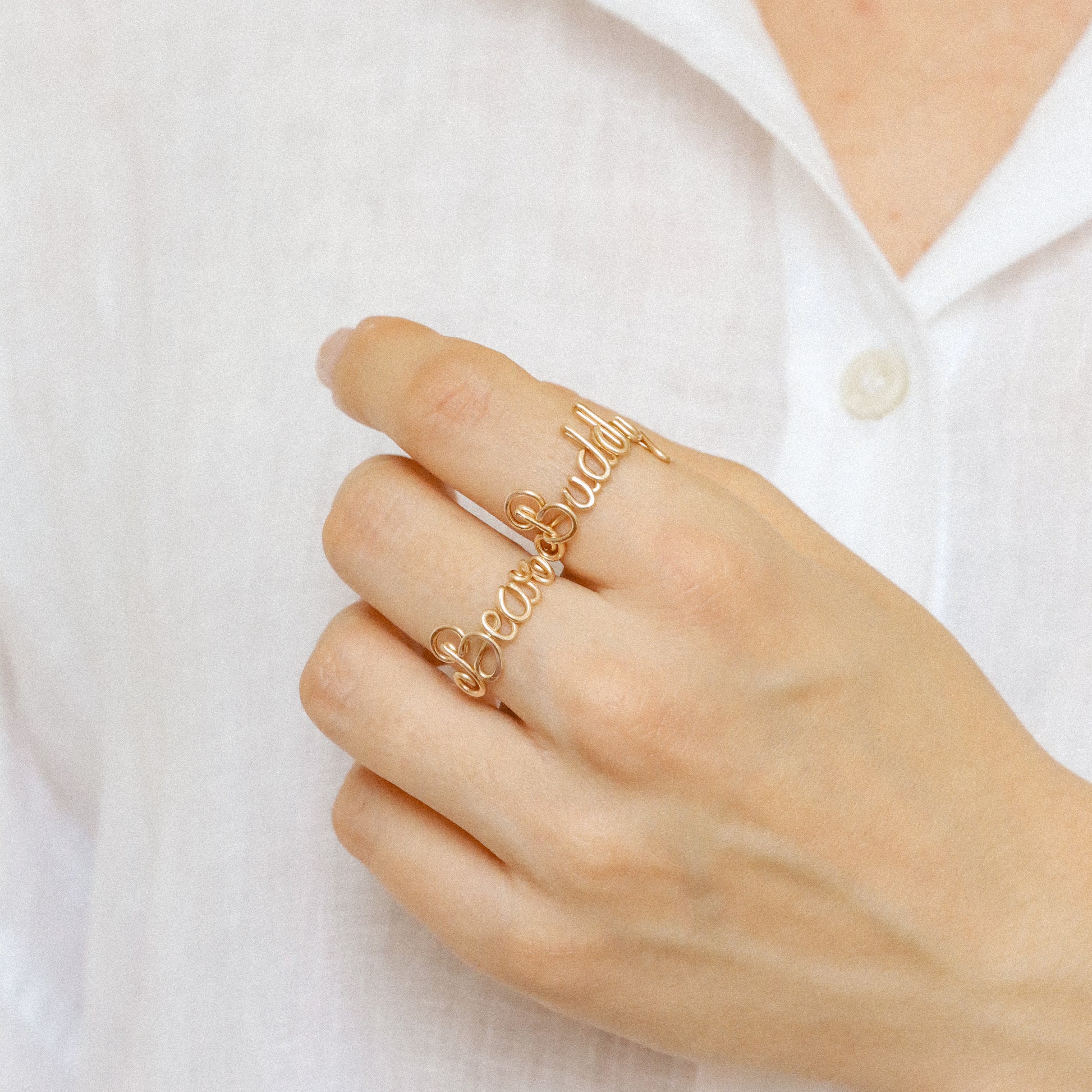 Stacking look featuring multiple handmade gold name rings like "Bear" and "Buddy".