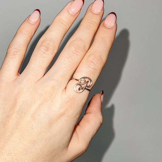 Handmade dainty gold wire ring featuring an uppercase cursive letter P, styled on a hand with red french tip nails.