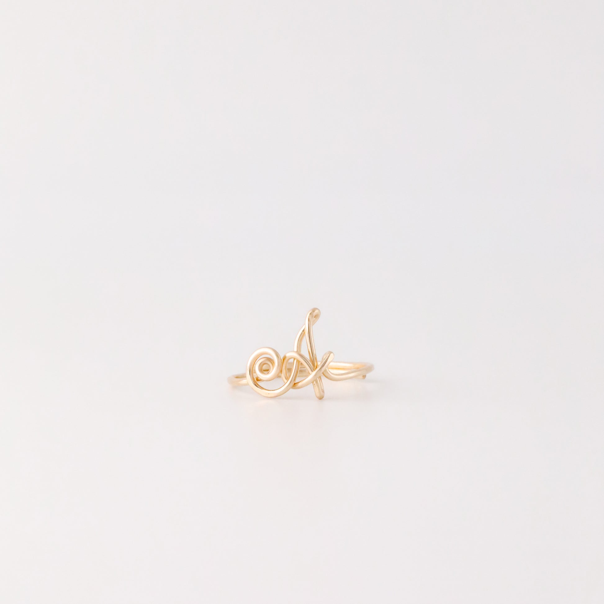 Dainty handmade gold wire ring with an uppercase cursive letter A.