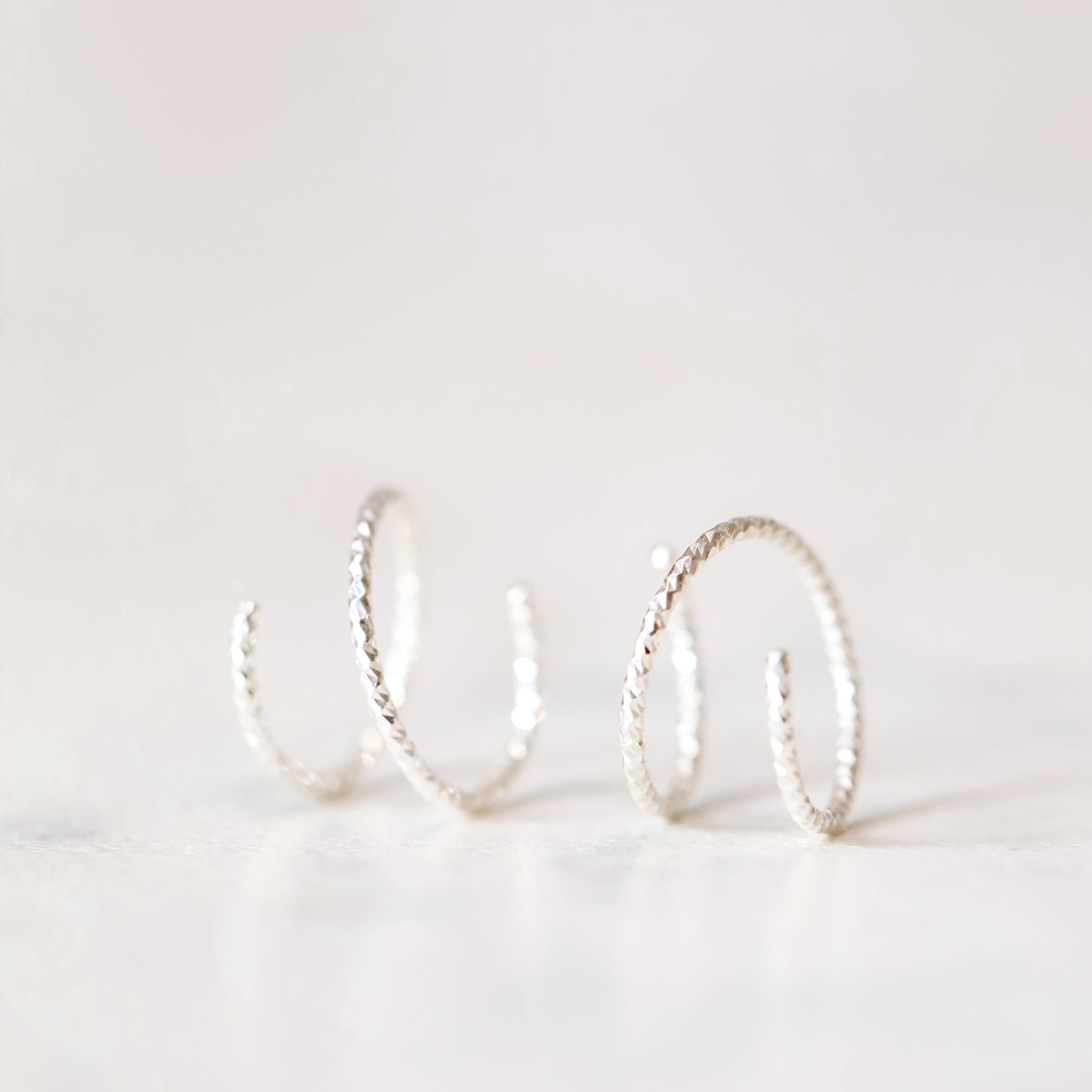 Minimal silver double hoop earrings on ear, tiny spiral earrings, sterling silver illusion double piercing jewelry