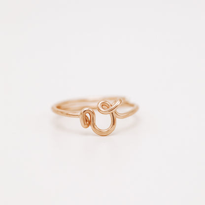 Handmade dainty rose gold wire ring with a lowercase cursive letter V design.