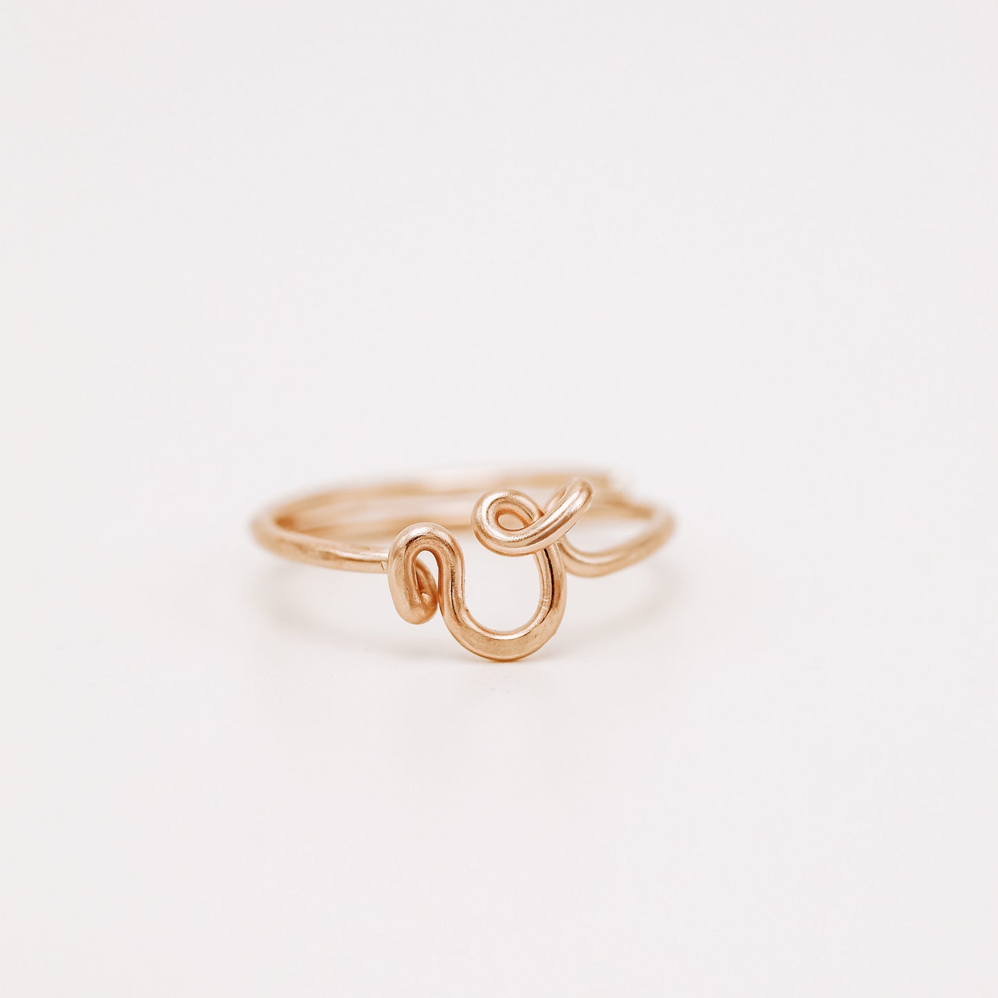 Handmade dainty rose gold wire ring with a lowercase cursive letter V design.