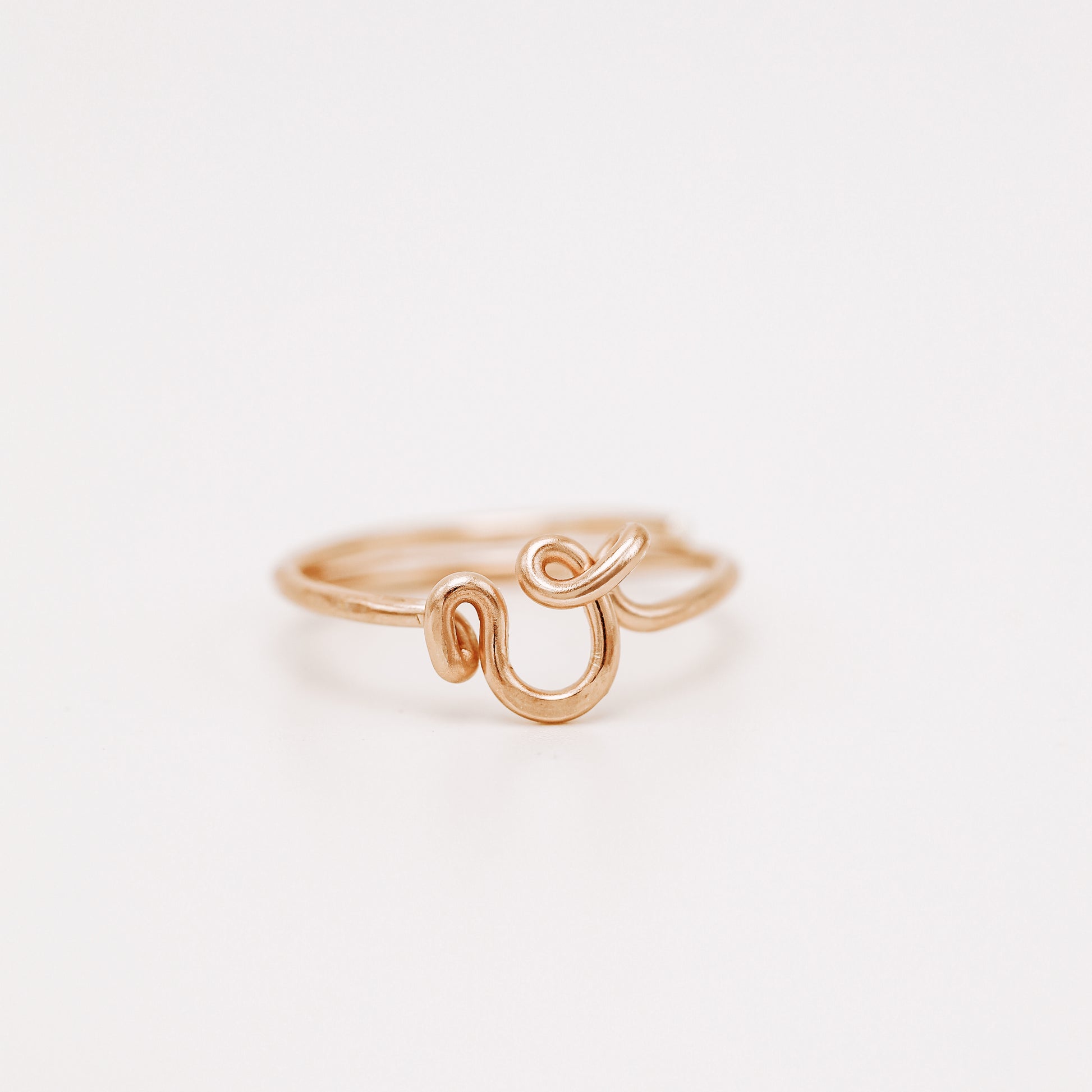 Handmade dainty rose gold wire ring with a lowercase cursive letter V design.