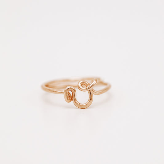 Handmade dainty rose gold wire ring with a lowercase cursive letter V design.