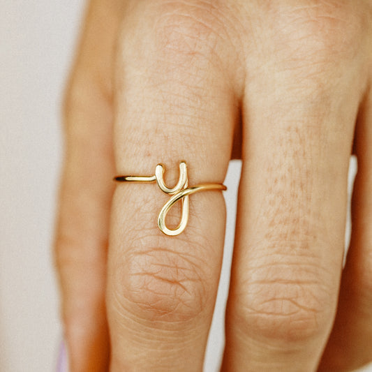 Close-up of a handmade 14k gold filled wire ring shaped into the letter Y on a woman's finger.