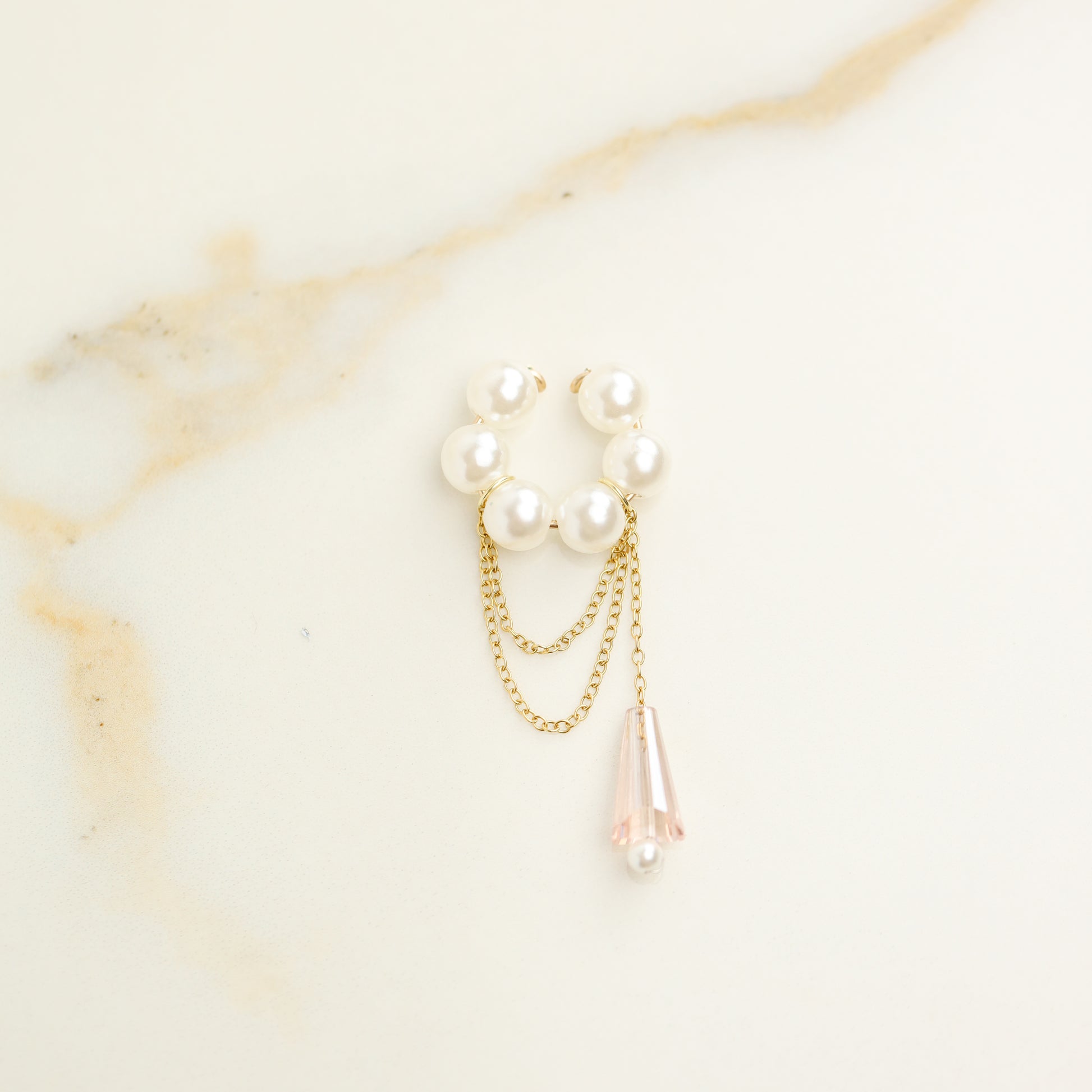 Dainty pearl crystal conch ear cuff shown as a no-piercing cartilage accessory, featuring artificial pearls around the conch area, delicate draped chains and a dangling faceted crystal drop, handmade and available in sterling silver 925, 14k gold filled or 14k rose gold filled.
