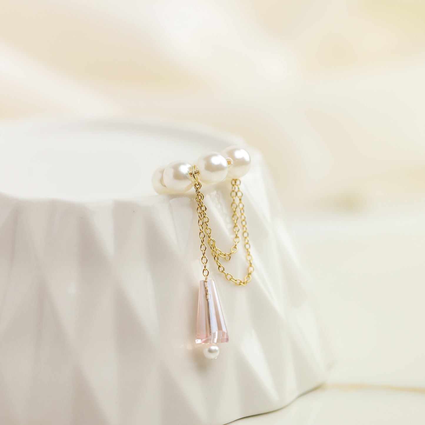Dainty pearl crystal conch ear cuff shown as a no-piercing cartilage accessory, featuring artificial pearls around the conch area, delicate draped chains and a dangling faceted crystal drop, handmade and available in sterling silver 925, 14k gold filled or 14k rose gold filled.