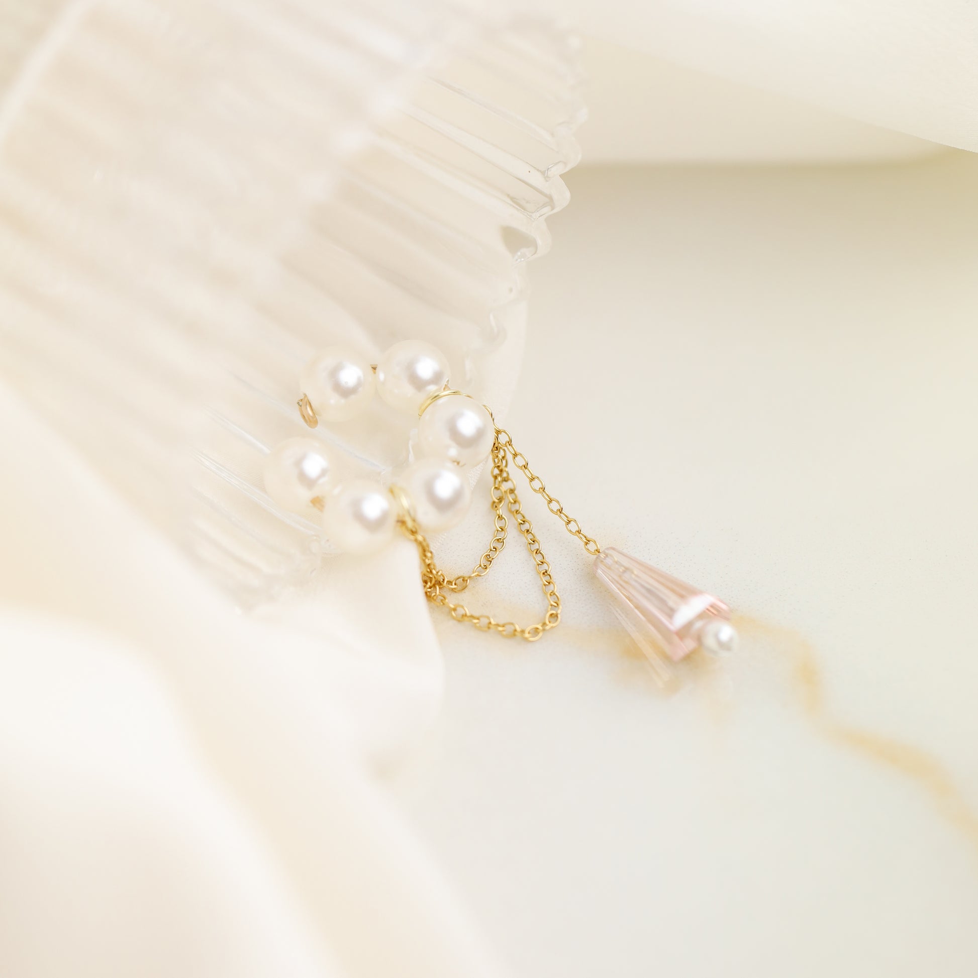 Dainty pearl crystal conch ear cuff shown as a no-piercing cartilage accessory, featuring artificial pearls around the conch area, delicate draped chains and a dangling faceted crystal drop, handmade and available in sterling silver 925, 14k gold filled or 14k rose gold filled.