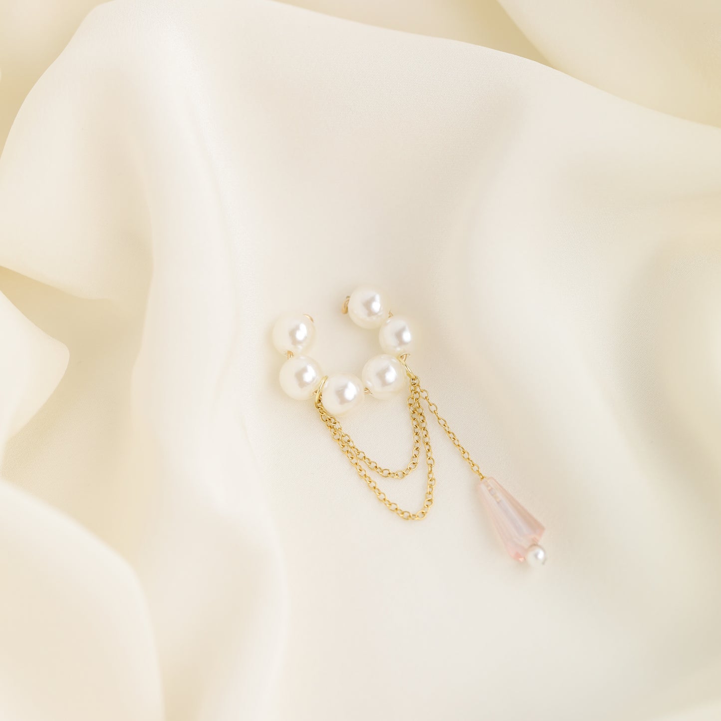 Dainty pearl crystal conch ear cuff shown as a no-piercing cartilage accessory, featuring artificial pearls around the conch area, delicate draped chains and a dangling faceted crystal drop, handmade and available in sterling silver 925, 14k gold filled or 14k rose gold filled.