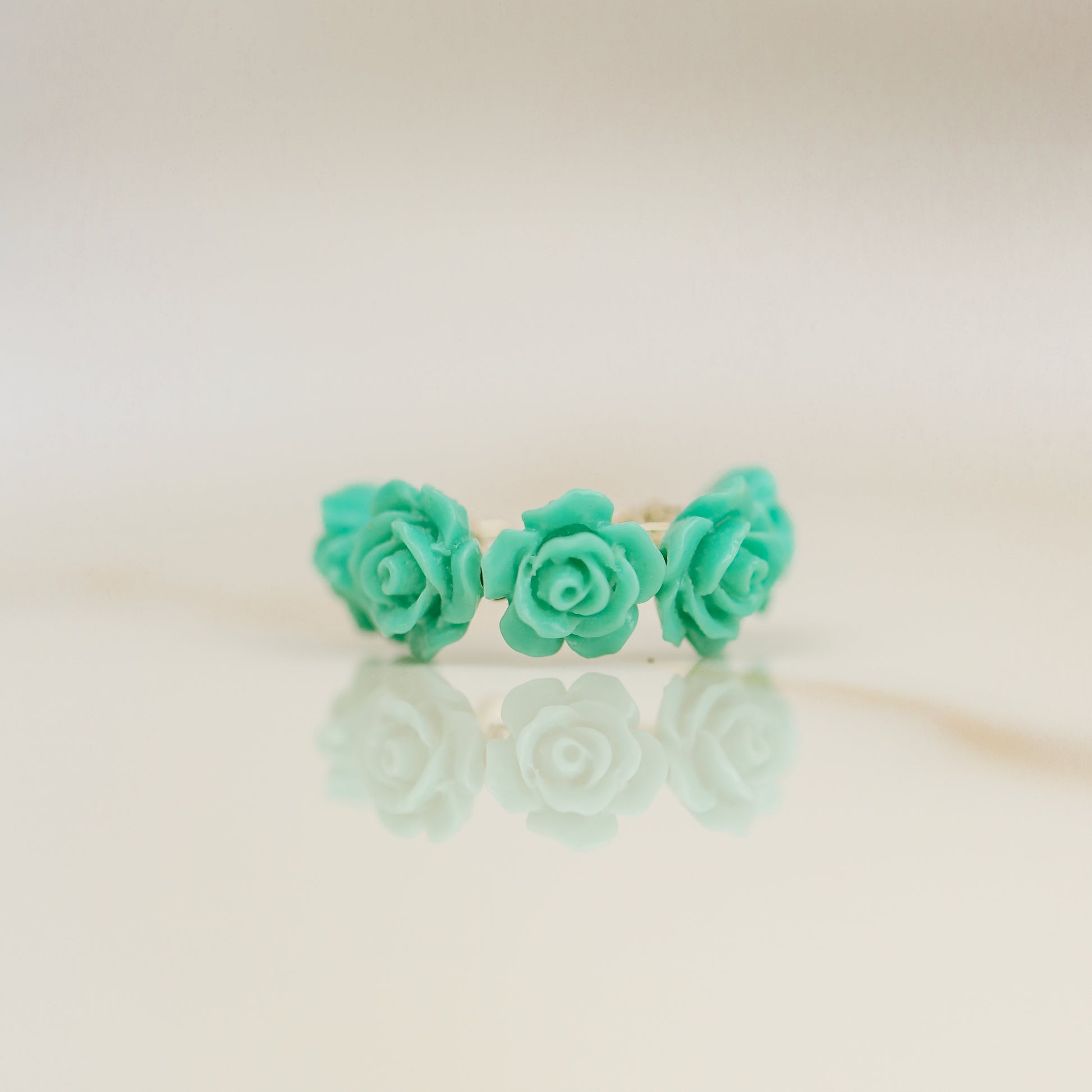 Turquoise aqua blue resin rose conch ear cuff worn on the ear as a colorful floral cartilage cuff