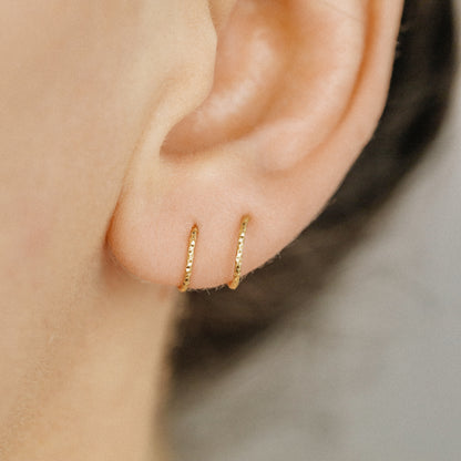 Minimal gold double hoop earrings with spiral twist design worn on ear, illusion of double piercing, diamond cut sterling silver jewelry