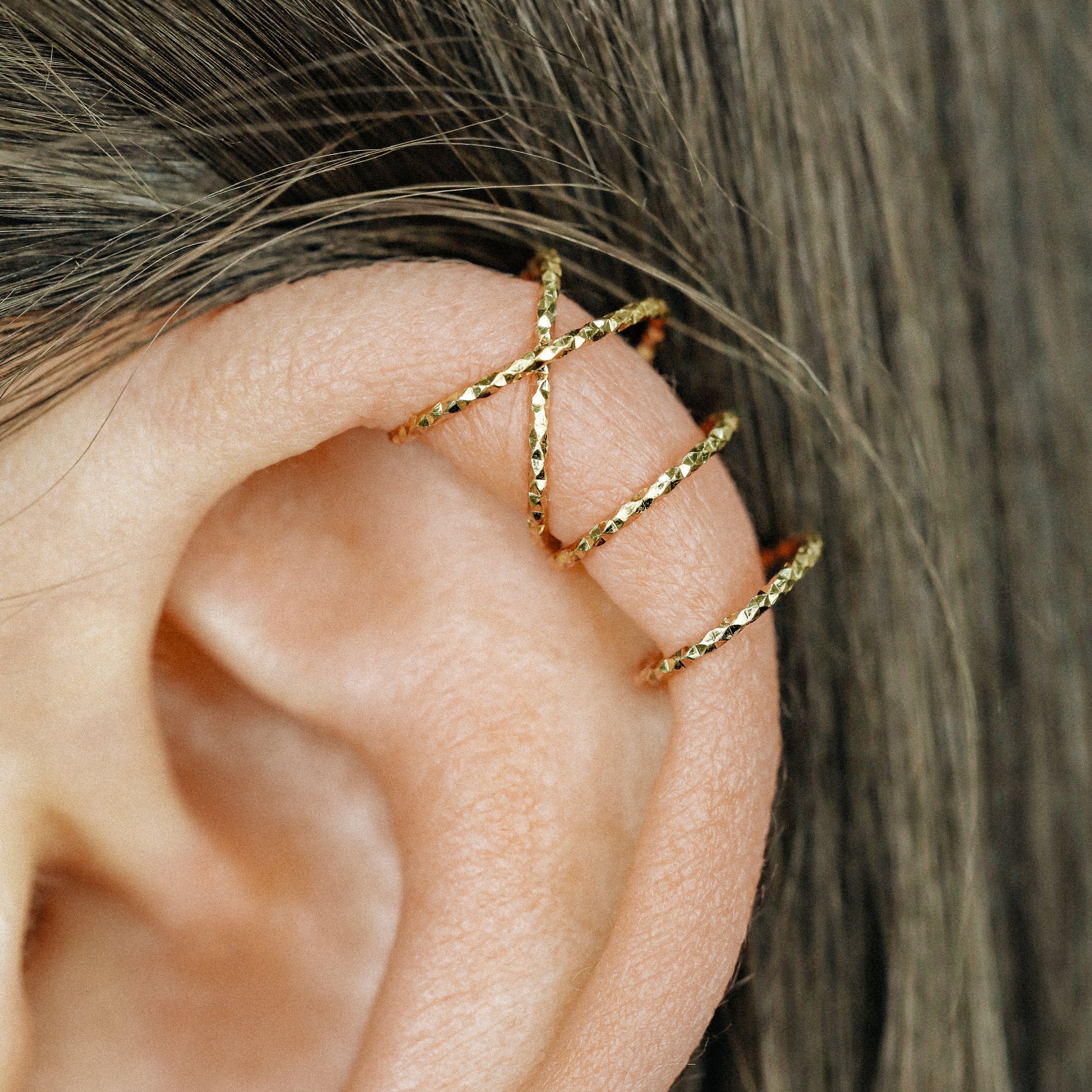 No-piercing double line and criss cross helix ear cuff worn on the upper ear, available in smooth and diamond cut finish options for cartilage styling.