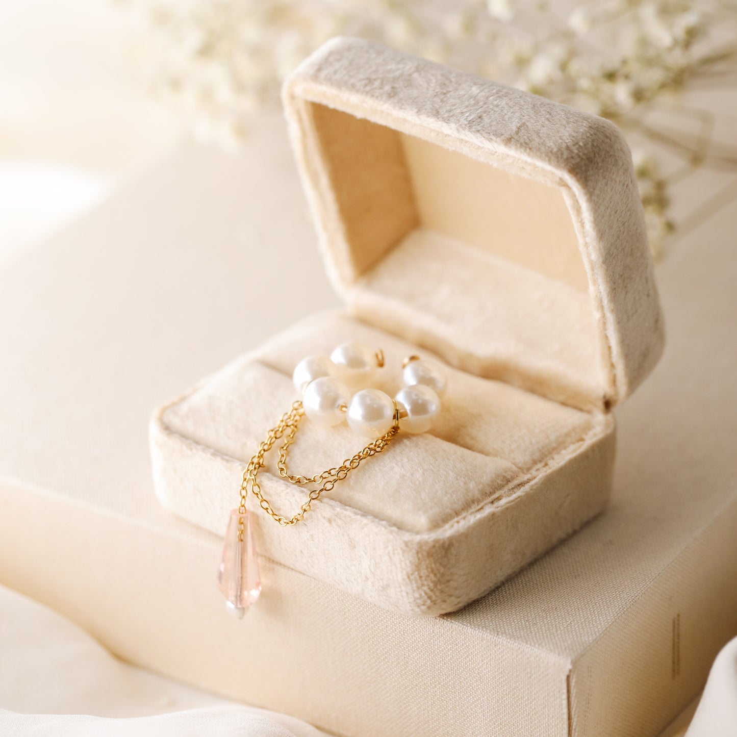 Dainty pearl crystal conch ear cuff shown as a no-piercing cartilage accessory, featuring artificial pearls around the conch area, delicate draped chains and a dangling faceted crystal drop, handmade and available in sterling silver 925, 14k gold filled or 14k rose gold filled.