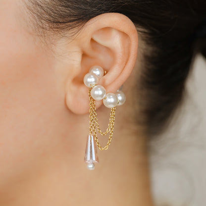 Dainty pearl crystal conch ear cuff shown as a no-piercing cartilage accessory, featuring artificial pearls around the conch area, delicate draped chains and a dangling faceted crystal drop, handmade and available in sterling silver 925, 14k gold filled or 14k rose gold filled.