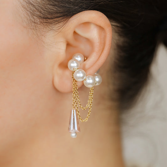 Dainty pearl crystal conch ear cuff shown as a no-piercing cartilage accessory, featuring artificial pearls around the conch area, delicate draped chains and a dangling faceted crystal drop, handmade and available in sterling silver 925, 14k gold filled or 14k rose gold filled.