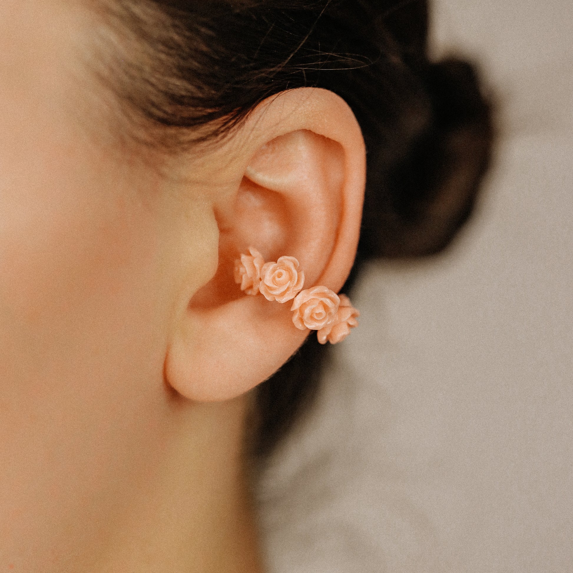 Peach coral resin rose ear cuff worn on the conch area with romantic floral detail