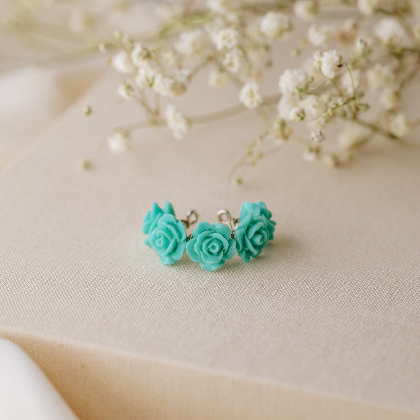 Turquoise aqua blue resin rose conch ear cuff worn on the ear as a colorful floral cartilage cuff