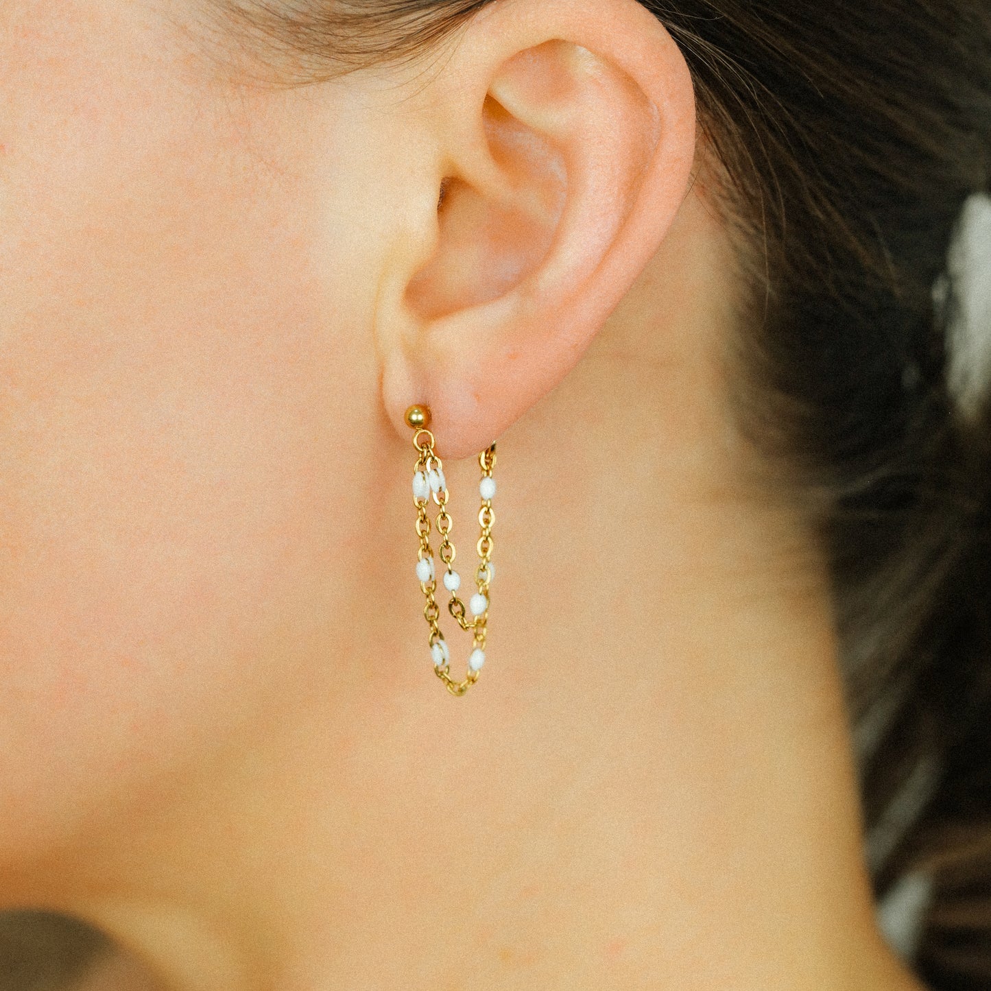 Gold double chain earrings styled on ear with delicate layered chain design