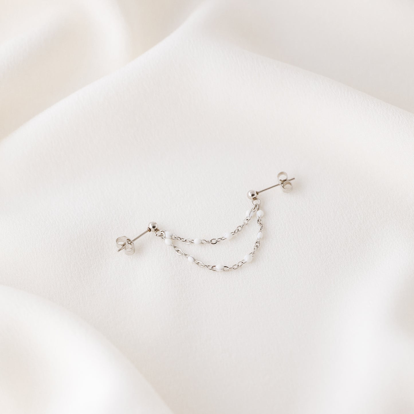 Silver double chain stud earring displayed on white fabric with push back closure