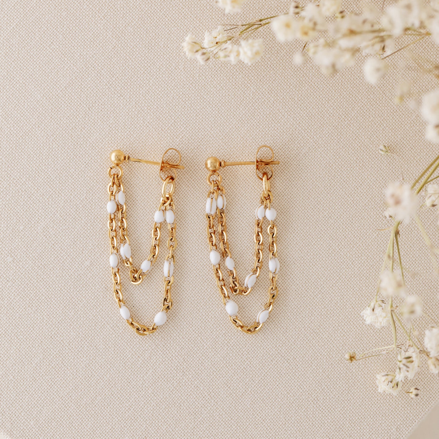Gold chain stud earrings with layered drop design and delicate white bead accents