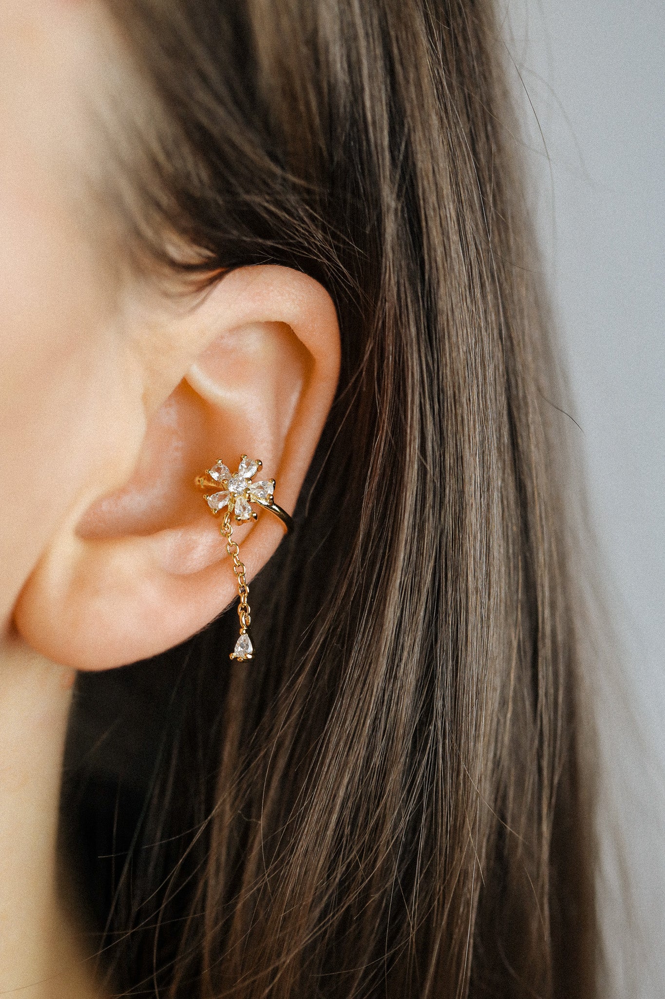 Sparkling flower ear cuff with dainty drop chain in 18k gold plated sterling silver and 925 silver, worn on cartilage without piercing.