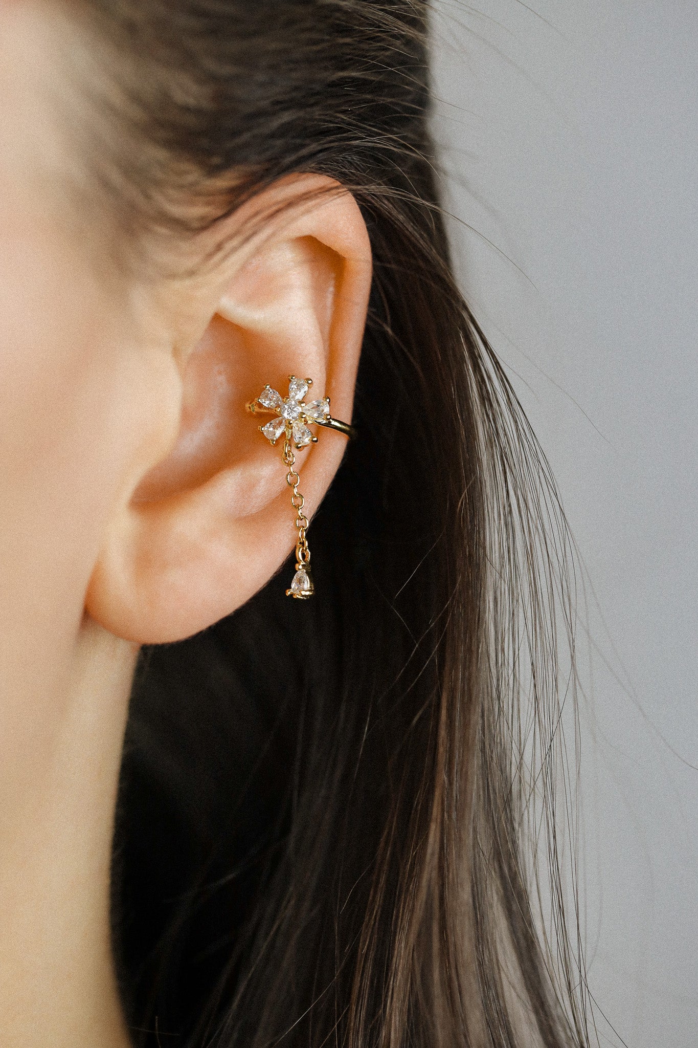 Sparkling flower ear cuff with dainty drop chain in 18k gold plated sterling silver and 925 silver, worn on cartilage without piercing.