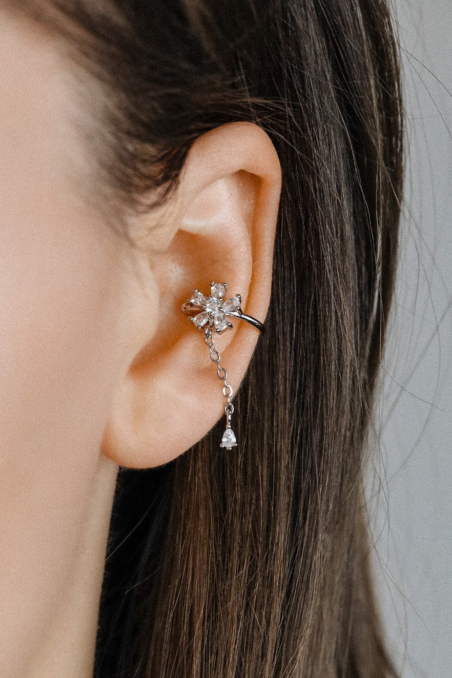Sparkling flower ear cuff with dainty drop chain in 18k gold plated sterling silver and 925 silver, worn on cartilage without piercing.