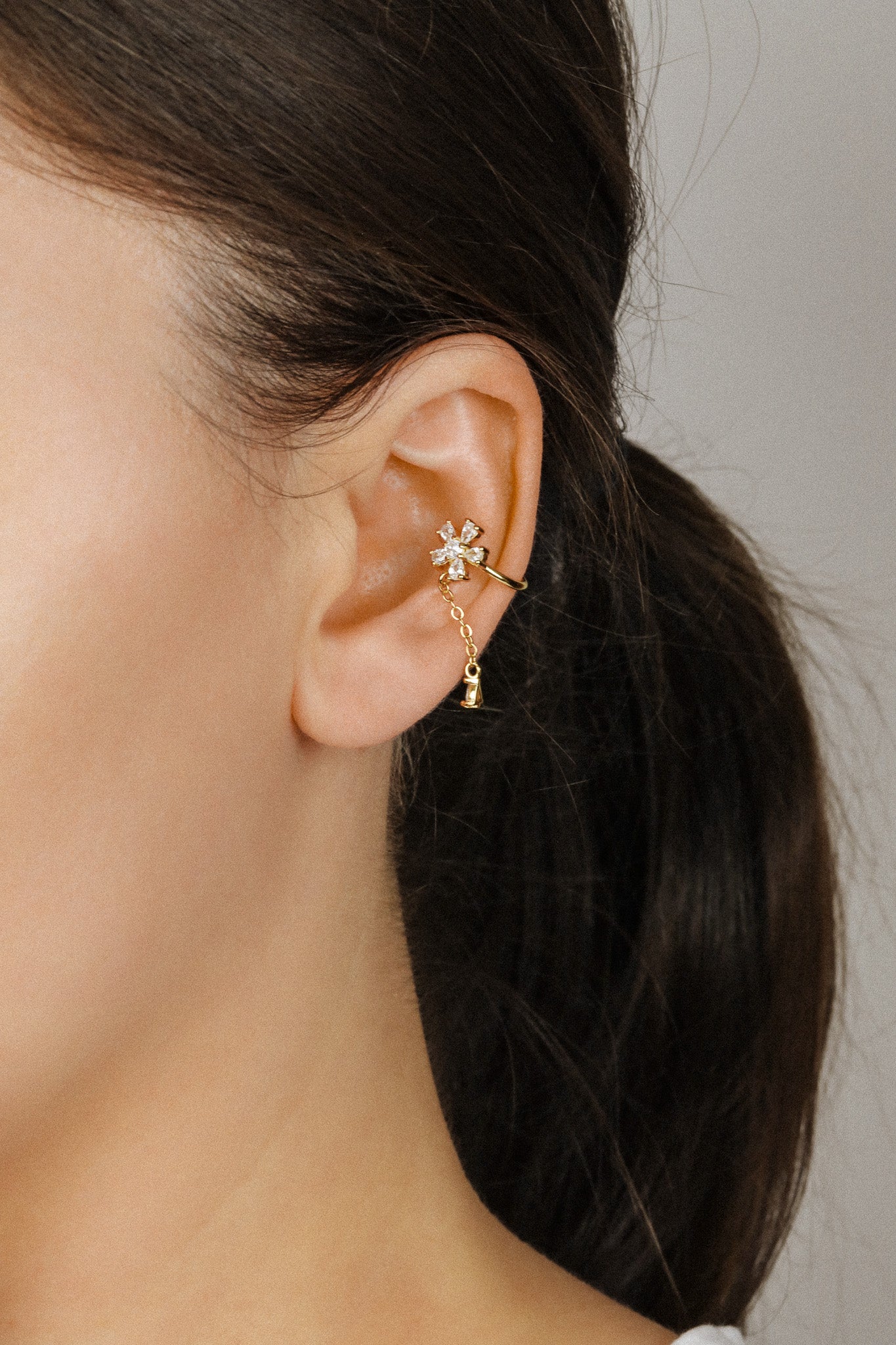 Sparkling flower ear cuff with dainty drop chain in 18k gold plated sterling silver and 925 silver, worn on cartilage without piercing.