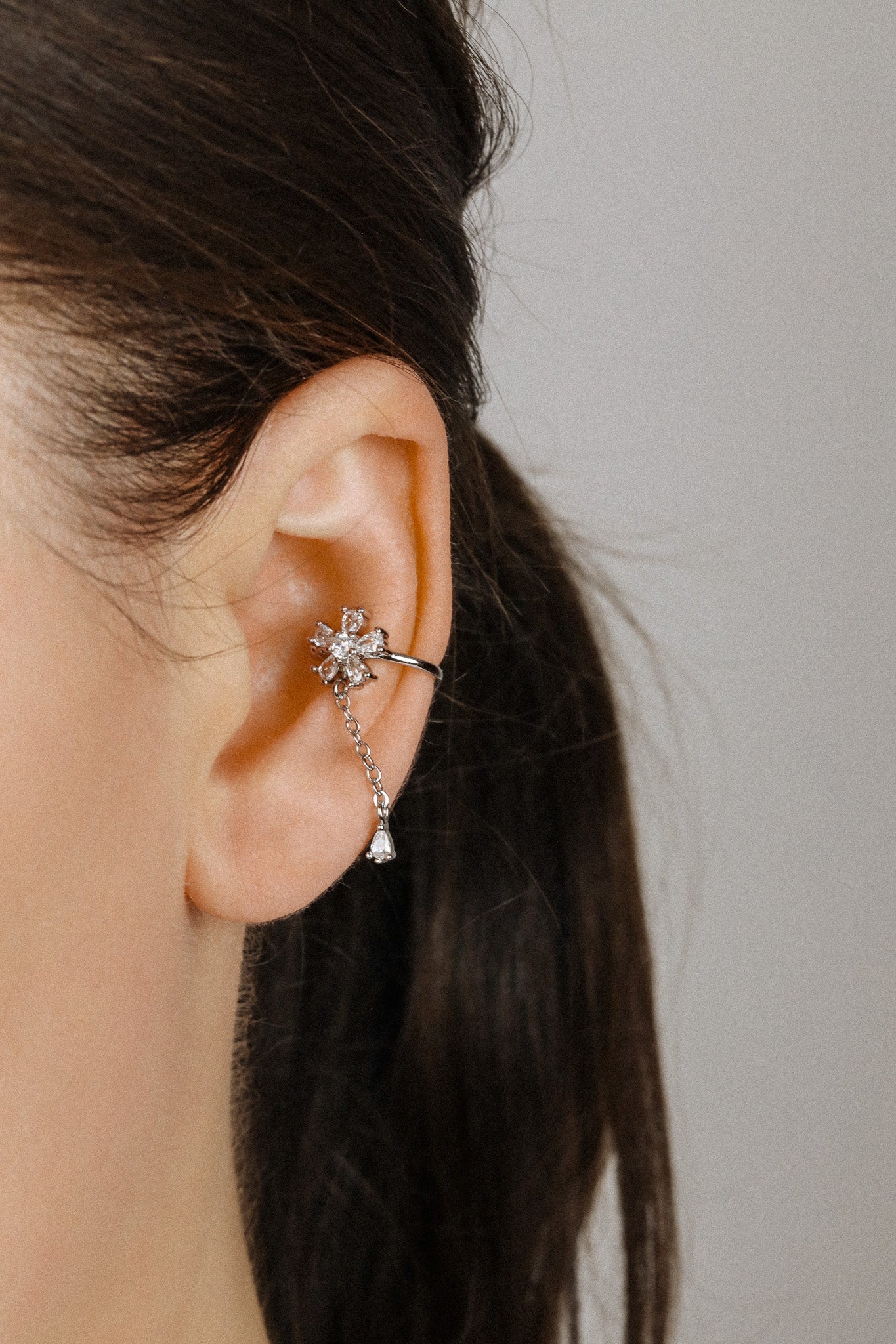 Sparkling flower ear cuff with dainty drop chain in 18k gold plated sterling silver and 925 silver, worn on cartilage without piercing.