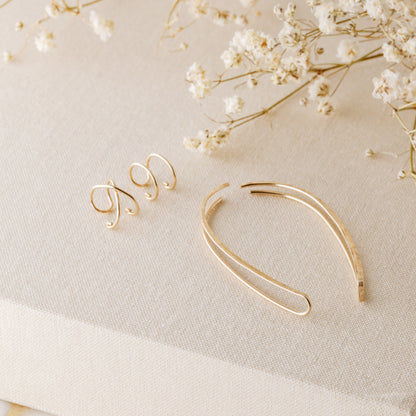 4 pieces ear climber set displayed on beige fabric with dried white flowers, featuring a pair of long hammered ear climbers, one Double Line no-piercing helix cuff and one Criss-Cross no-piercing helix cuff in a warm gold finish.