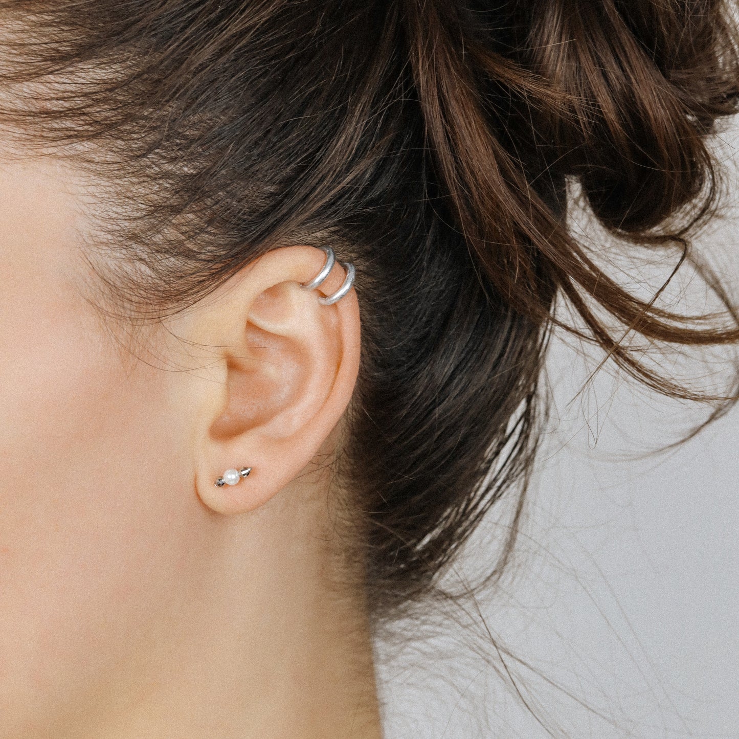 Adjustable no-piercing helix ear cuff shown worn on the upper cartilage area, available in silver, black and soft gold with Double Line and Criss-Cross style options for a bold stacked ear look.