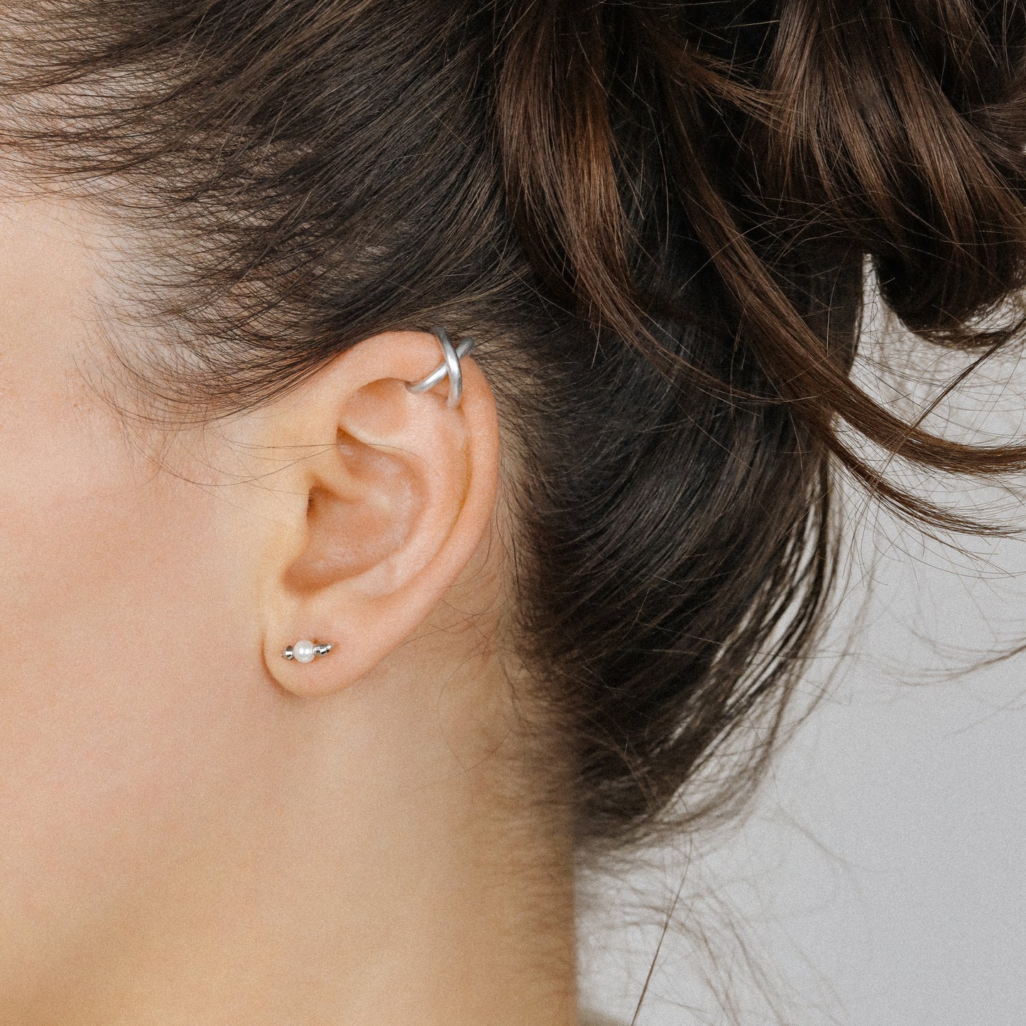 Adjustable no-piercing helix ear cuff shown worn on the upper cartilage area, available in silver, black and soft gold with Double Line and Criss-Cross style options for a bold stacked ear look.