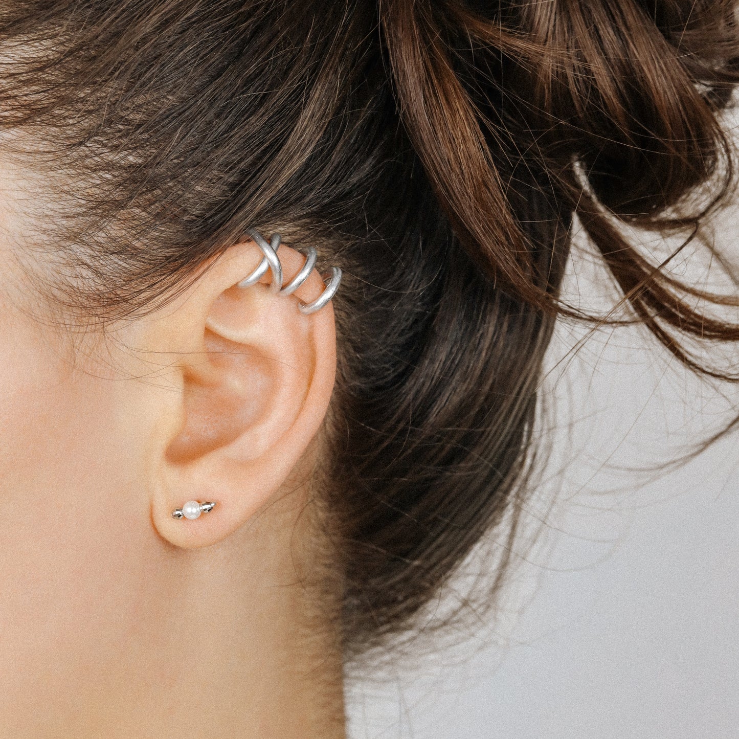 Adjustable no-piercing helix ear cuff shown worn on the upper cartilage area, available in silver, black and soft gold with Double Line and Criss-Cross style options for a bold stacked ear look.