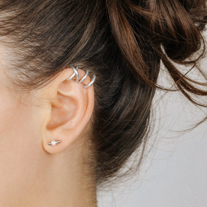 Adjustable no-piercing helix ear cuff shown worn on the upper cartilage area, available in silver, black and soft gold with Double Line and Criss-Cross style options for a bold stacked ear look.