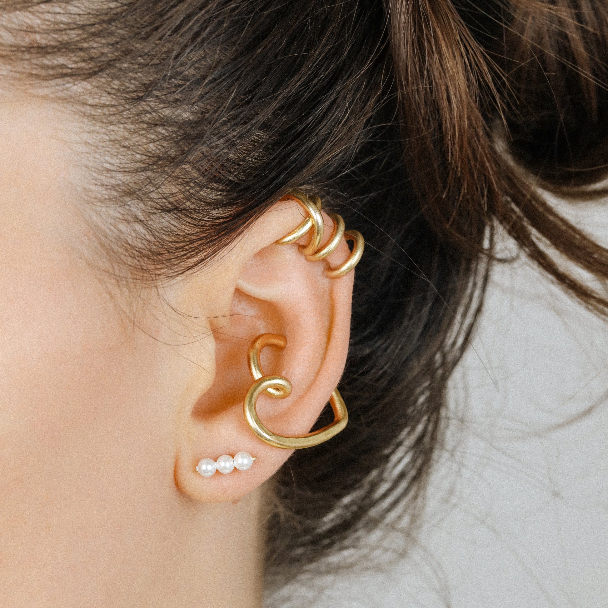 Adjustable no-piercing helix ear cuff shown worn on the upper cartilage area, available in soft gold, silver and black with Double Line and Criss-Cross style options for a bold stacked ear look.