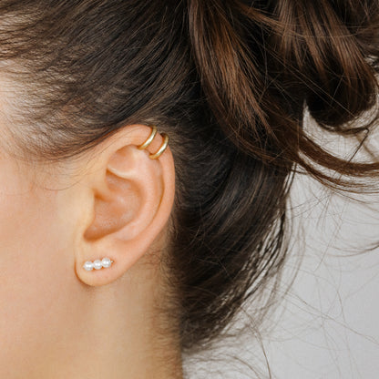 Adjustable no-piercing helix ear cuff shown worn on the upper cartilage area, available in silver, black and soft gold with Double Line and Criss-Cross style options for a bold stacked ear look.