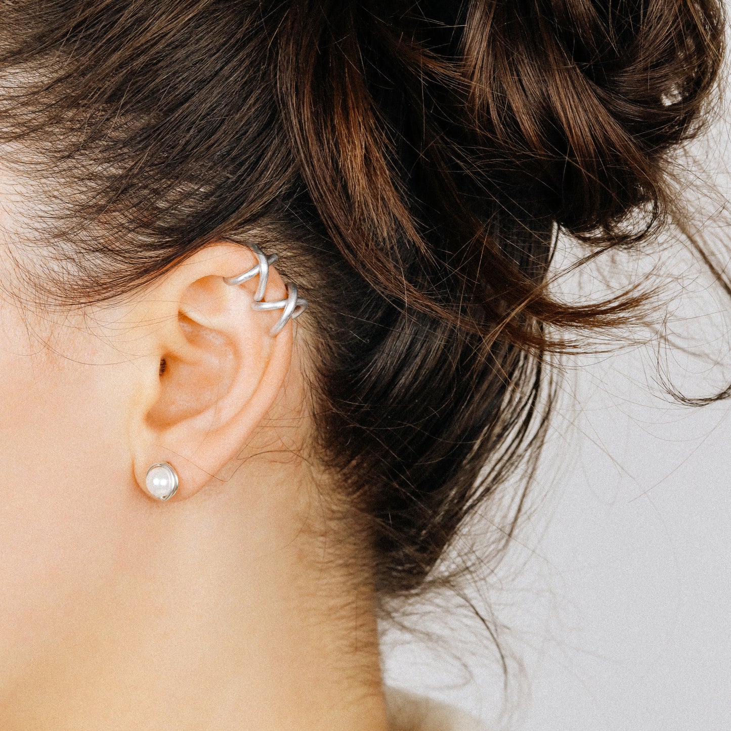 Adjustable no-piercing helix ear cuff shown worn on the upper cartilage area, available in silver, black and soft gold with Double Line and Criss-Cross style options for a bold stacked ear look.
