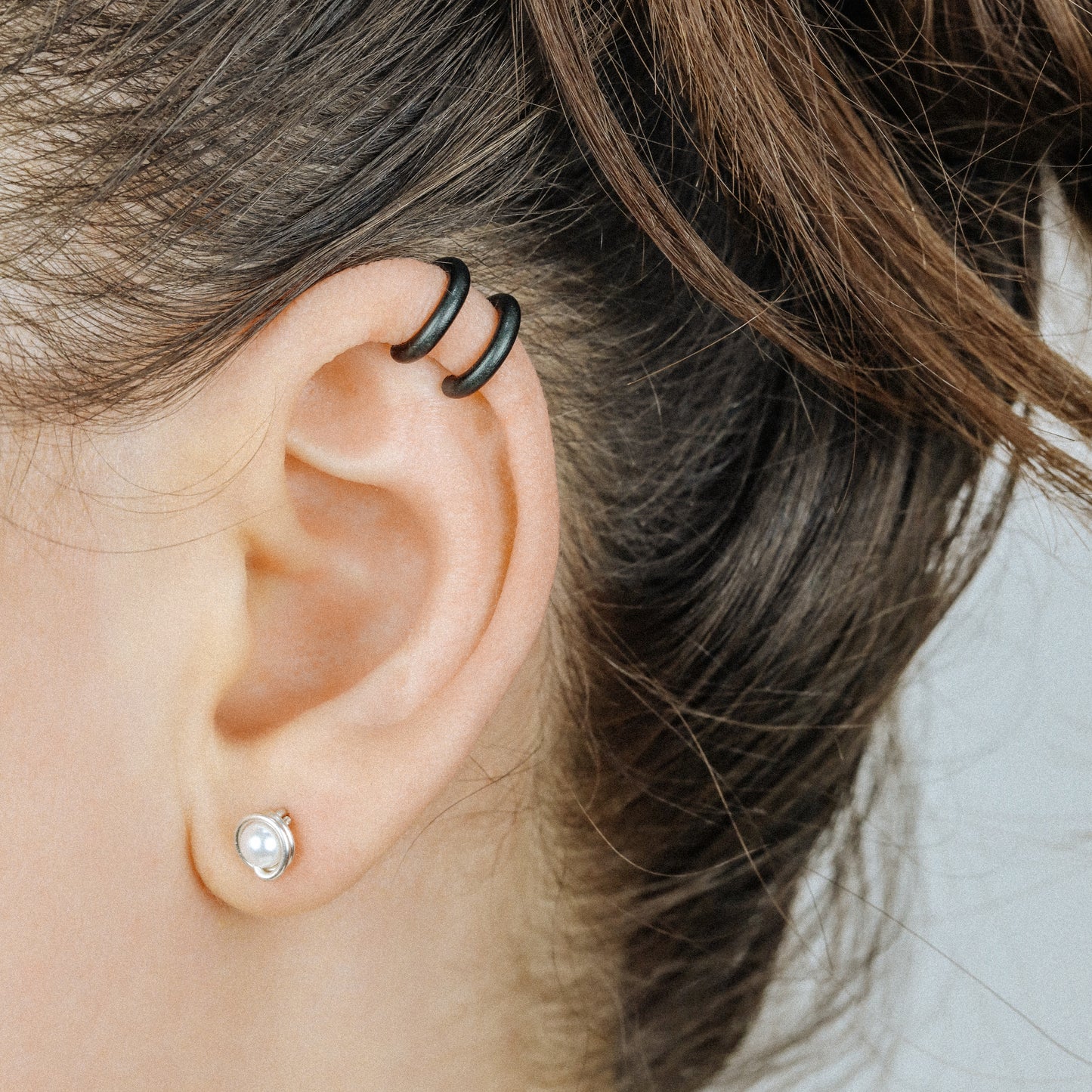 Adjustable no-piercing helix ear cuff shown worn on the upper cartilage area, available in silver, black and soft gold with Double Line and Criss-Cross style options for a bold stacked ear look.