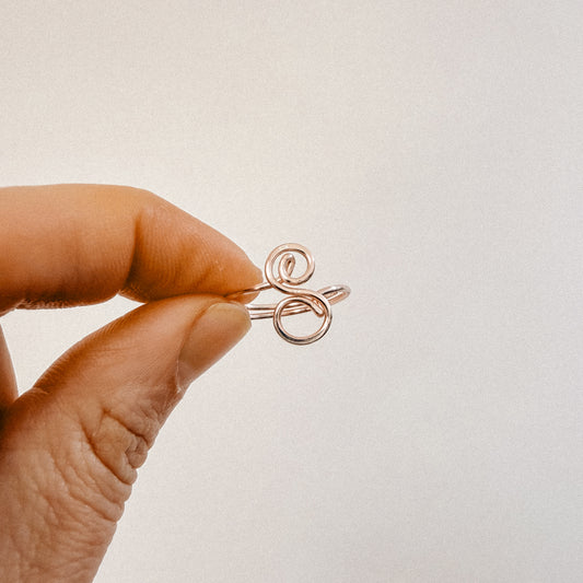 Handmade rose gold wire ring featuring an uppercase cursive letter S held between fingers.