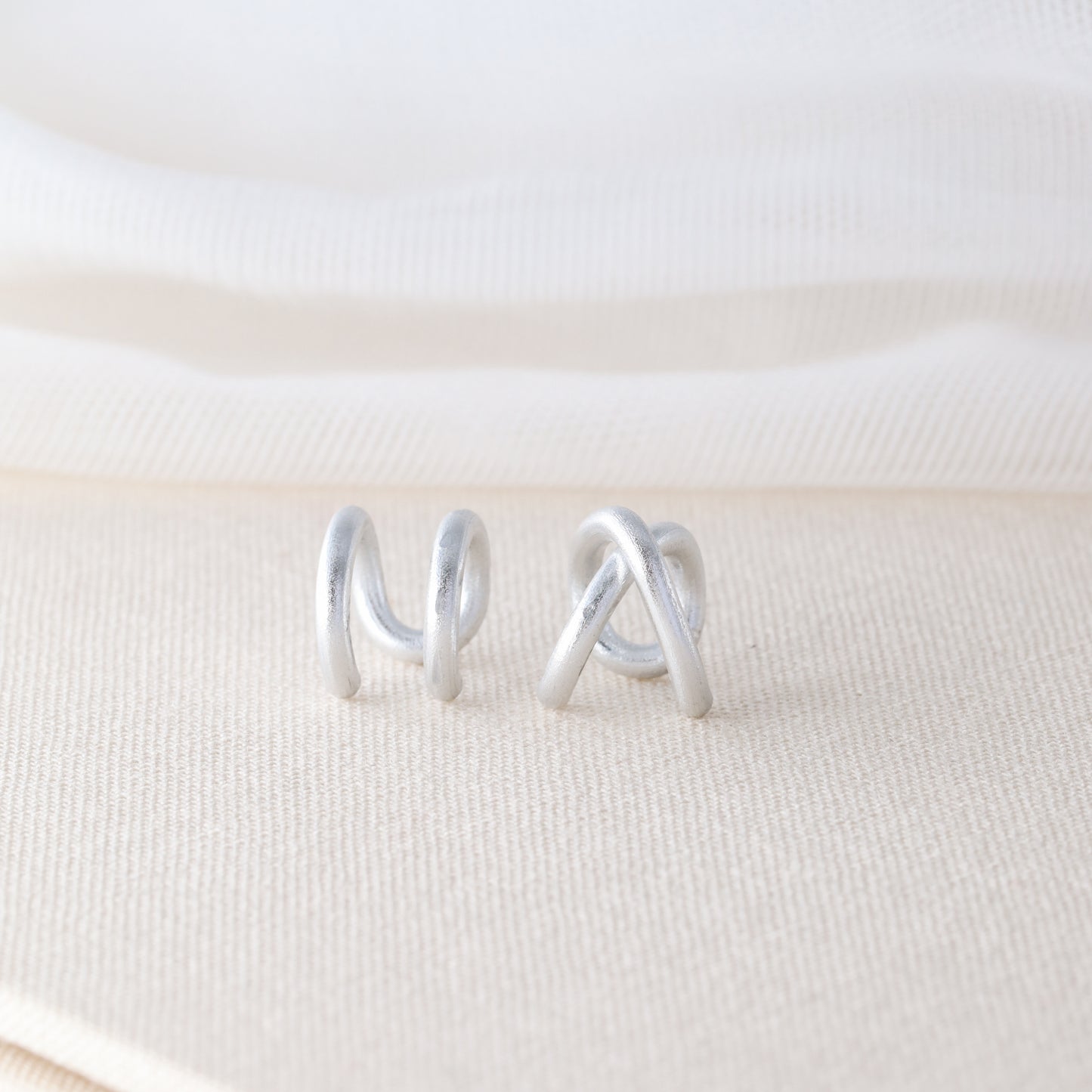 Adjustable no-piercing helix ear cuff shown worn on the upper cartilage area, available in silver, black and soft gold with Double Line and Criss-Cross style options for a bold stacked ear look.