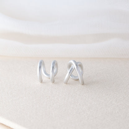 Adjustable no-piercing helix ear cuff shown worn on the upper cartilage area, available in silver, black and soft gold with Double Line and Criss-Cross style options for a bold stacked ear look.
