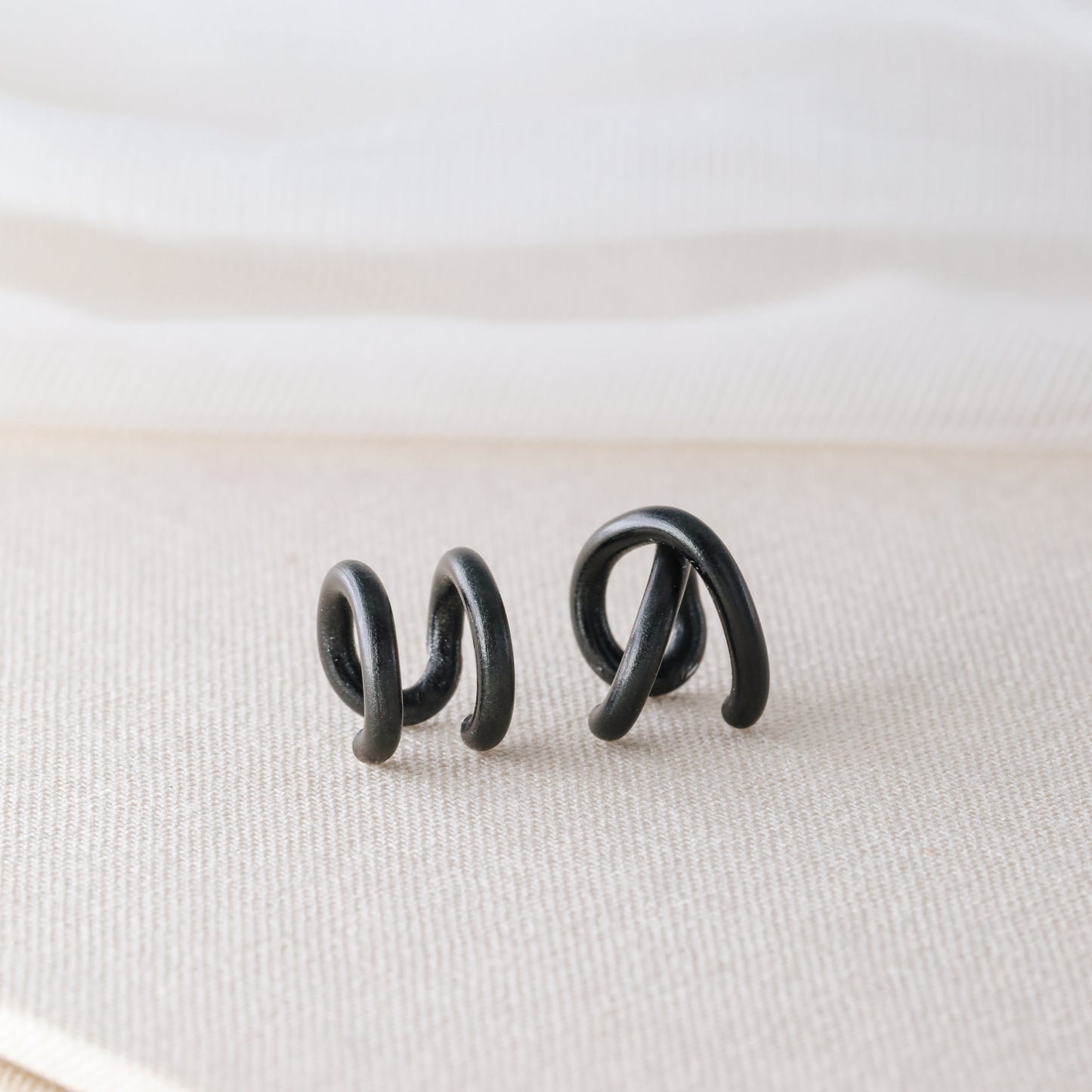 Adjustable no-piercing helix ear cuff shown worn on the upper cartilage area, available in silver, black and soft gold with Double Line and Criss-Cross style options for a bold stacked ear look.