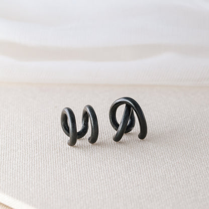 Adjustable no-piercing helix ear cuff shown worn on the upper cartilage area, available in silver, black and soft gold with Double Line and Criss-Cross style options for a bold stacked ear look.