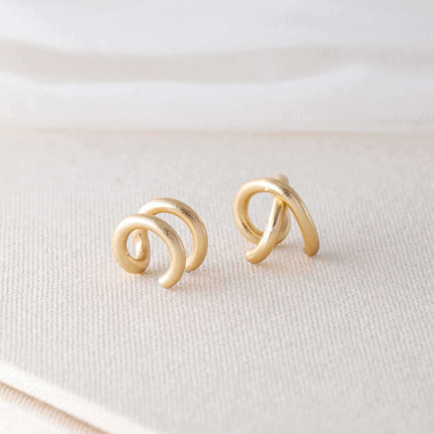 Adjustable no-piercing helix ear cuff shown worn on the upper cartilage area, available in silver, black and soft gold with Double Line and Criss-Cross style options for a bold stacked ear look.