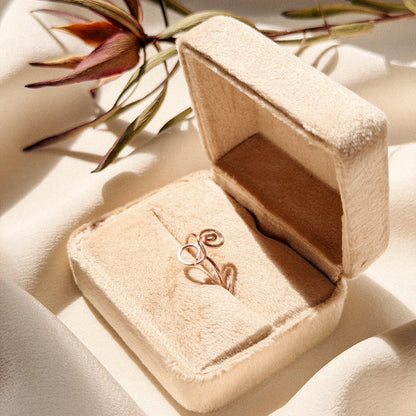 Elegant uppercase cursive letter S wire ring inside a velvet gift box, surrounded by soft fabric and flowers.
