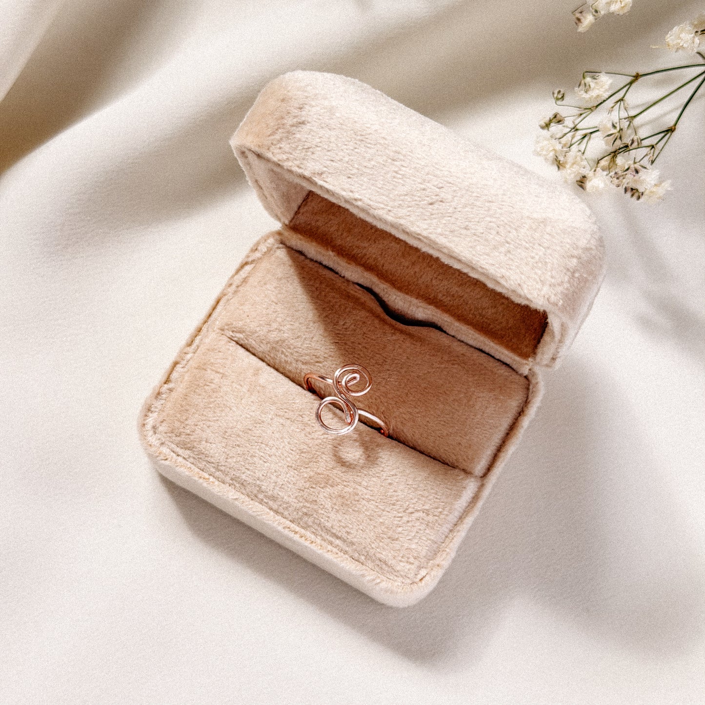 Handmade uppercase cursive letter S ring presented in a luxury beige velvet jewelry box with warm lighting.