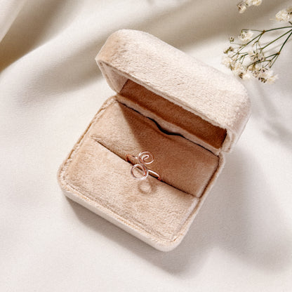 Handmade uppercase cursive letter S ring presented in a luxury beige velvet jewelry box with warm lighting.