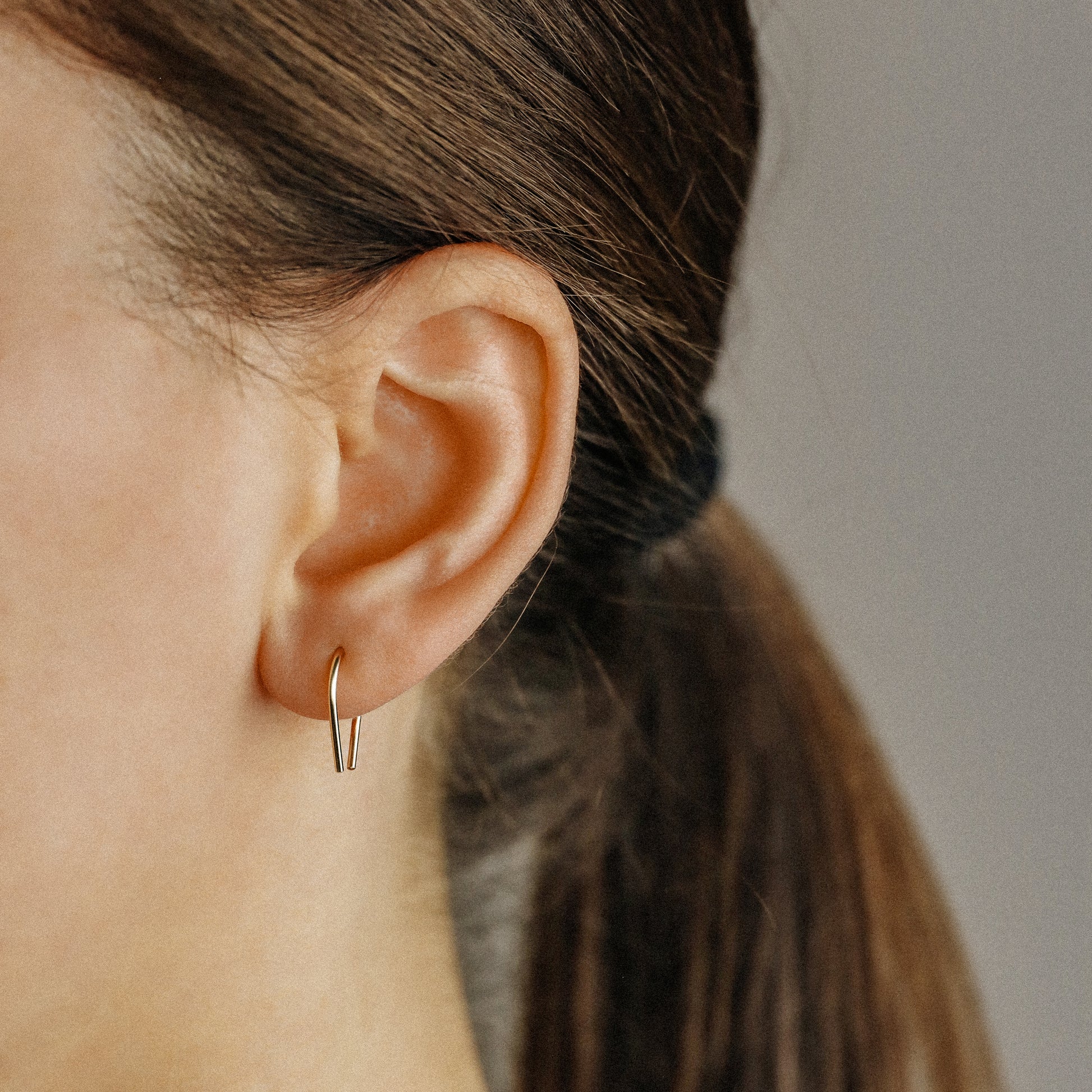 Side profile of modern U shaped earrings worn on earlobe
