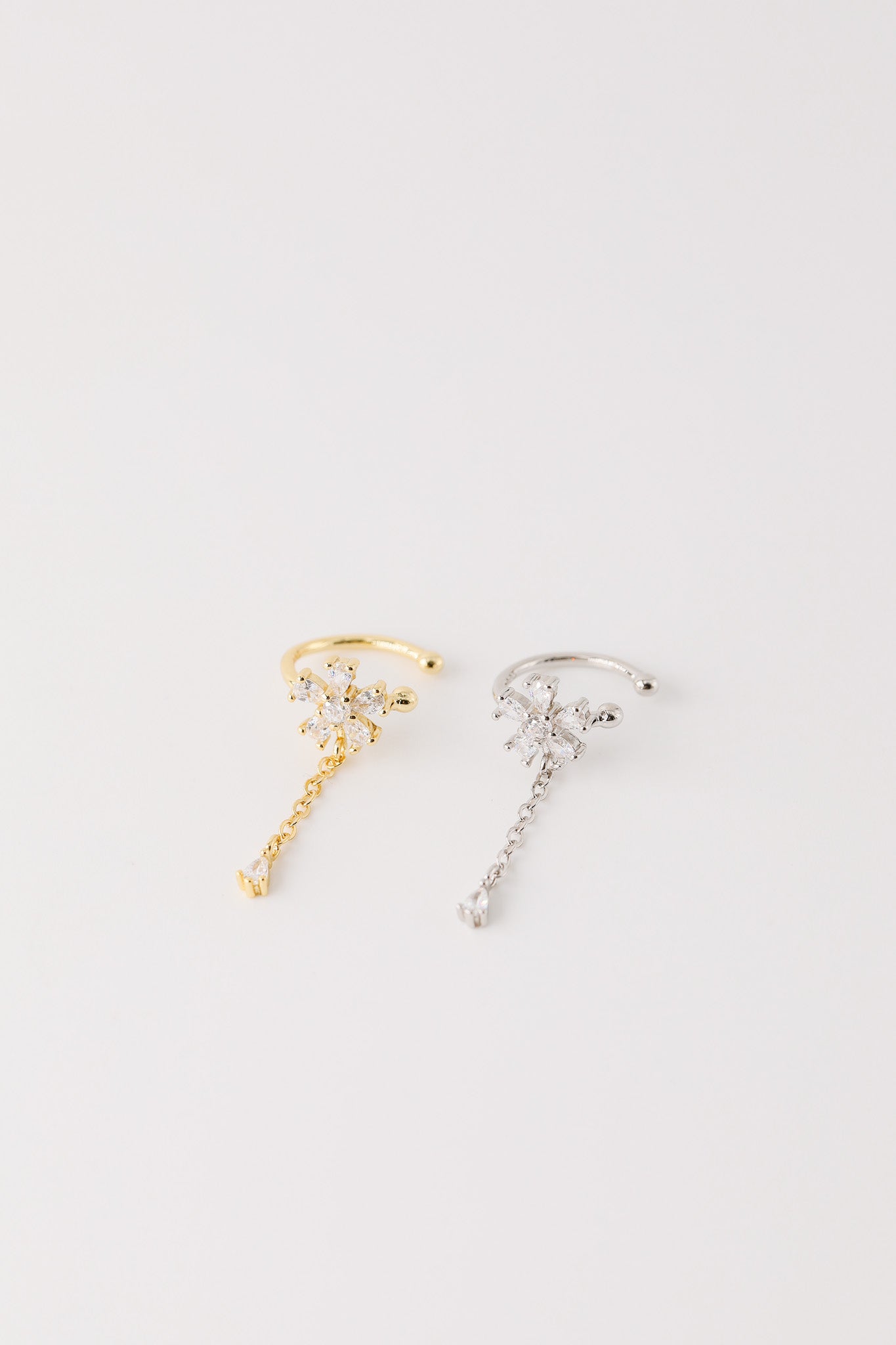 Sparkling flower ear cuff with dainty drop chain in 18k gold plated sterling silver and 925 silver, worn on cartilage without piercing.