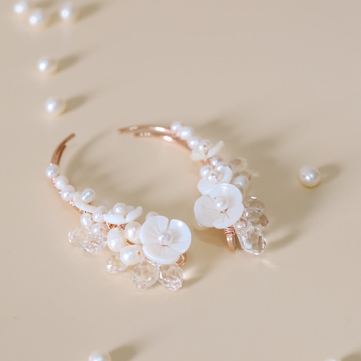 Close-up of matching bridal ear climbers decorated with AA+ freshwater pearls, carved mother-of-pearl flowers and transparent faceted crystal drops, showing the coordinated left and right design.